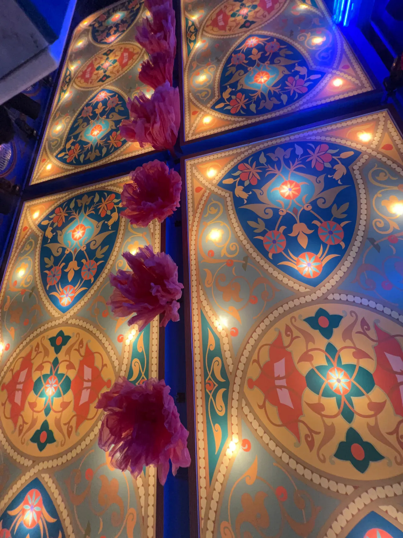 Close view of the illuminated ceiling patterns and suspended flowers at Club Boho